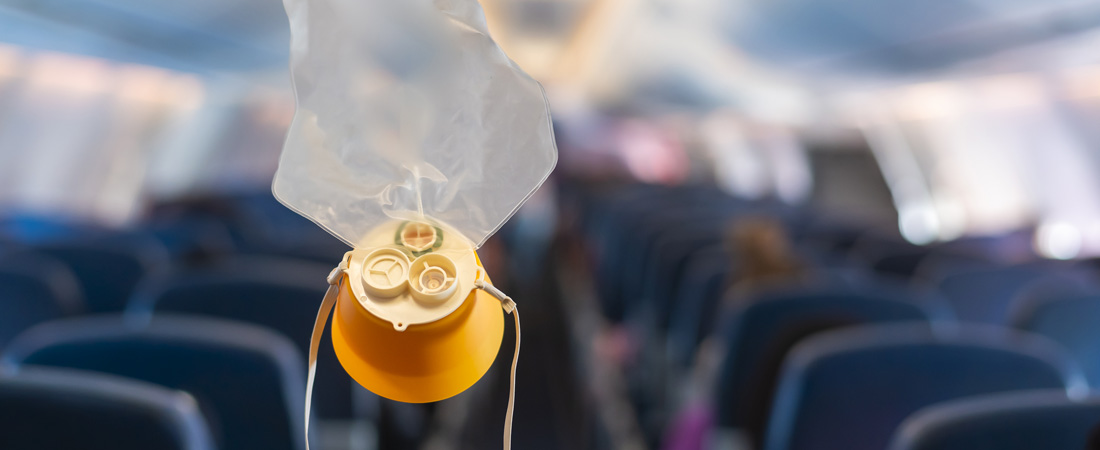 Primer plano de una máscara de oxígeno amarilla desplegada en la cabina de un avión.