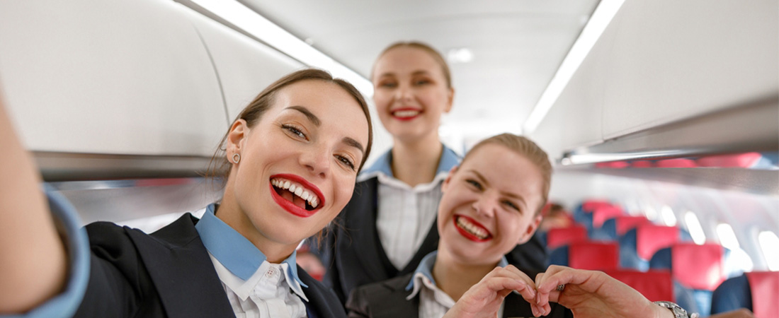 Tres azafatas sonrientes tomándose una selfie dentro de un avión.