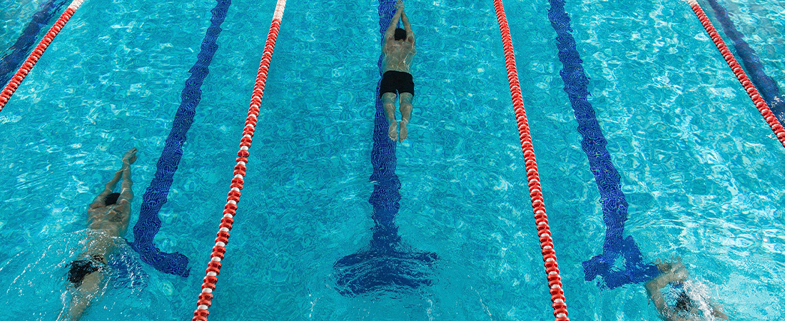 Vista aérea de una piscina de entrenamiento con carriles donde varias personas realizan pruebas de natación.