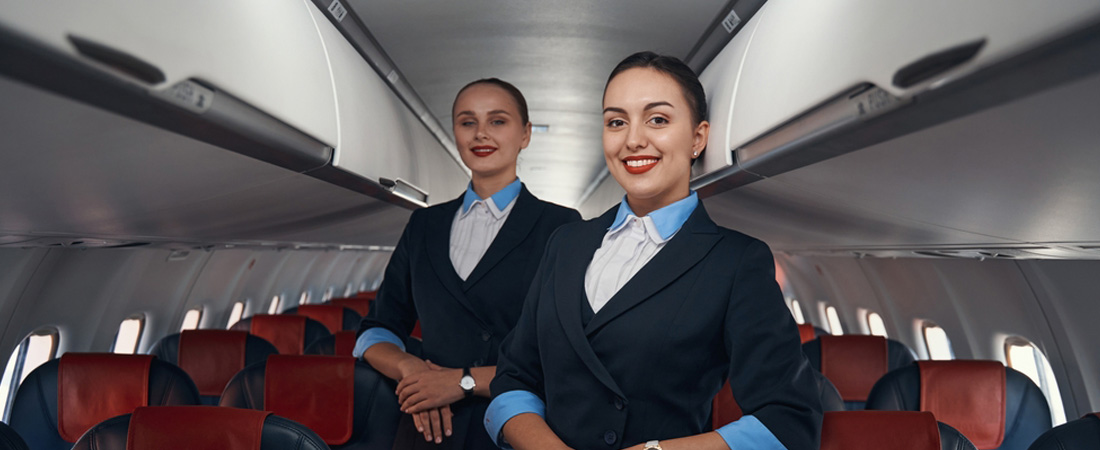 Dos azafatas sonrientes dentro de un avión.